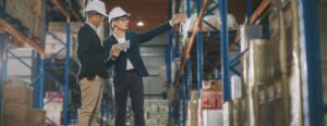 man and woman in hard hats at warehouse
